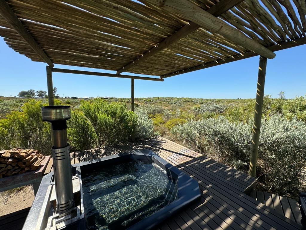 HopefieldFarm Stay: Enjoy Fynbos Views & Wood Fired Hot Tub的甲板上的热水浴池,带凉棚