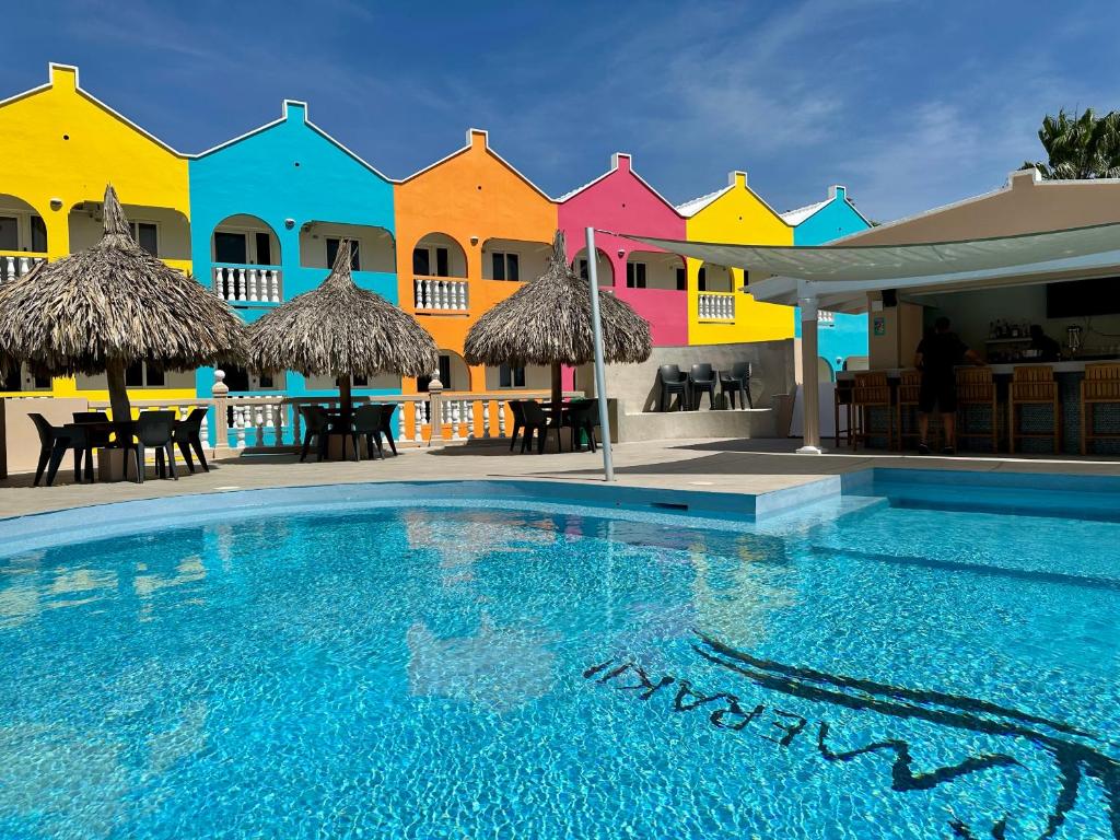 威廉斯塔德MERAKII SEAVIEW ESCAPE CURACAO的一座游泳池,位于一排色彩缤纷的房屋前