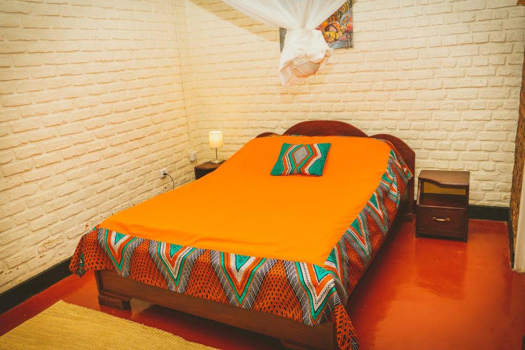 RuhengeriRoom in Guest room - Isange Paradise Resort的砖墙房间里一张橙色的床