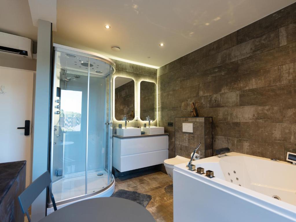 奥德多普Luxe kamer B&B Gezond aan Zee, met jacuzzi en stoomsauna, de wellnestuin buiten is te huur voor privé gebruik tegen meerprijs的浴室配有2个盥洗盆、浴缸和淋浴。