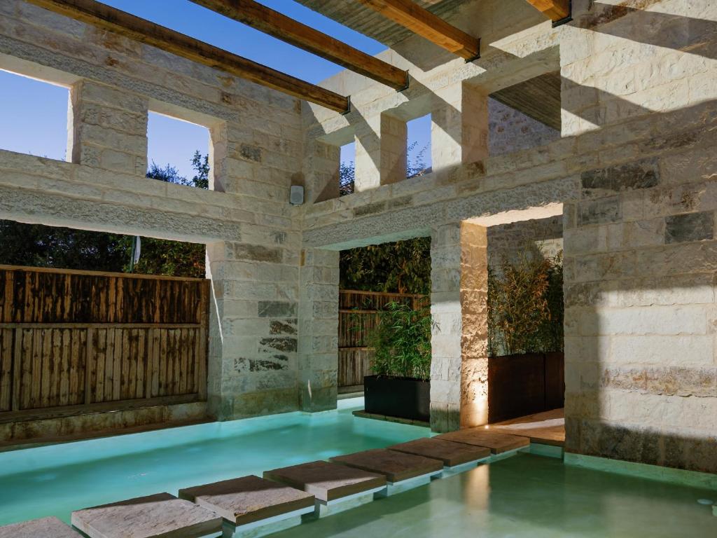 罗希姆诺Amalen Suites Adults Only的一座石头墙建筑中的游泳池