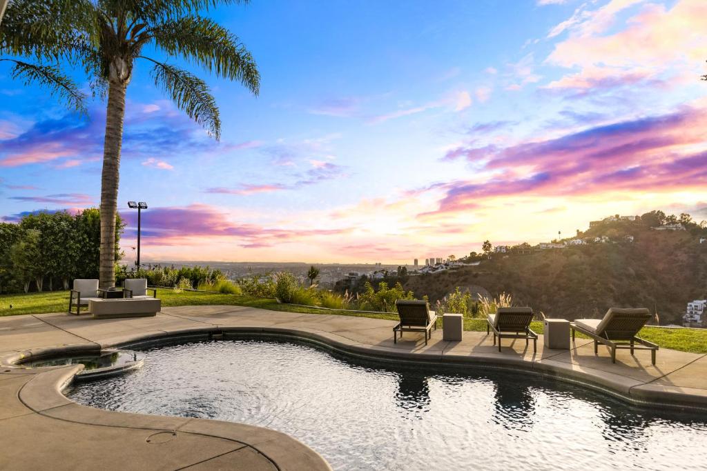 洛杉矶Hollywood Hills Luxury Modern Home with Pool & Sunset views的一个带椅子的游泳池,并种植了棕榈树