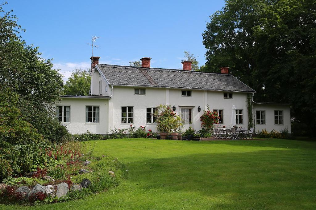 法伦Olsbacka Gård的白色的房子,大院子,草坪上有四柱木头