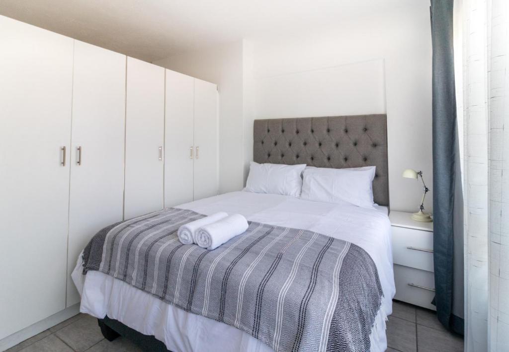 德班Wavecrest 301 Holiday Apartment的一间卧室配有一张带灰色和白色毯子的床