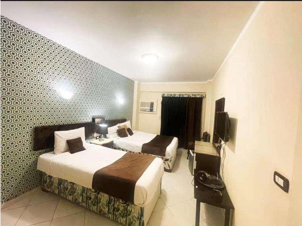 赫尔格达Golden Sun Hotel - Hurghada的酒店客房设有两张床和电视。