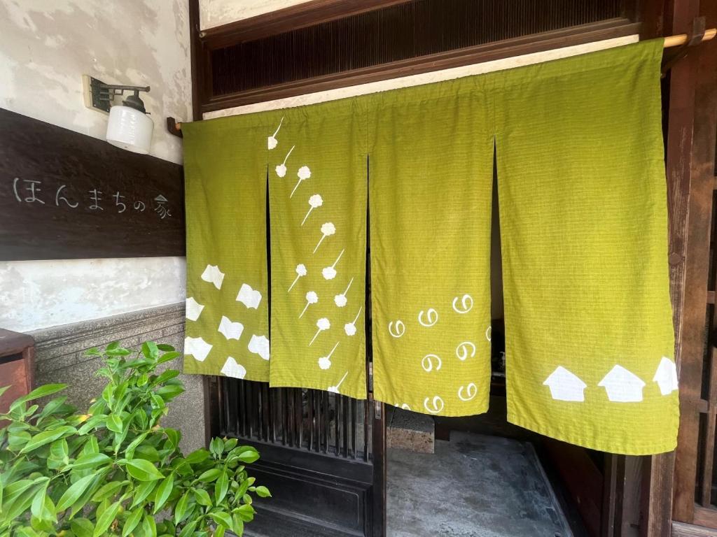 Yokota（一棟貸切）町家体験ゲストハウス「ほんまちの家」〜高岡市の伝統的な古民家～的绿窗帘,门上装有植物