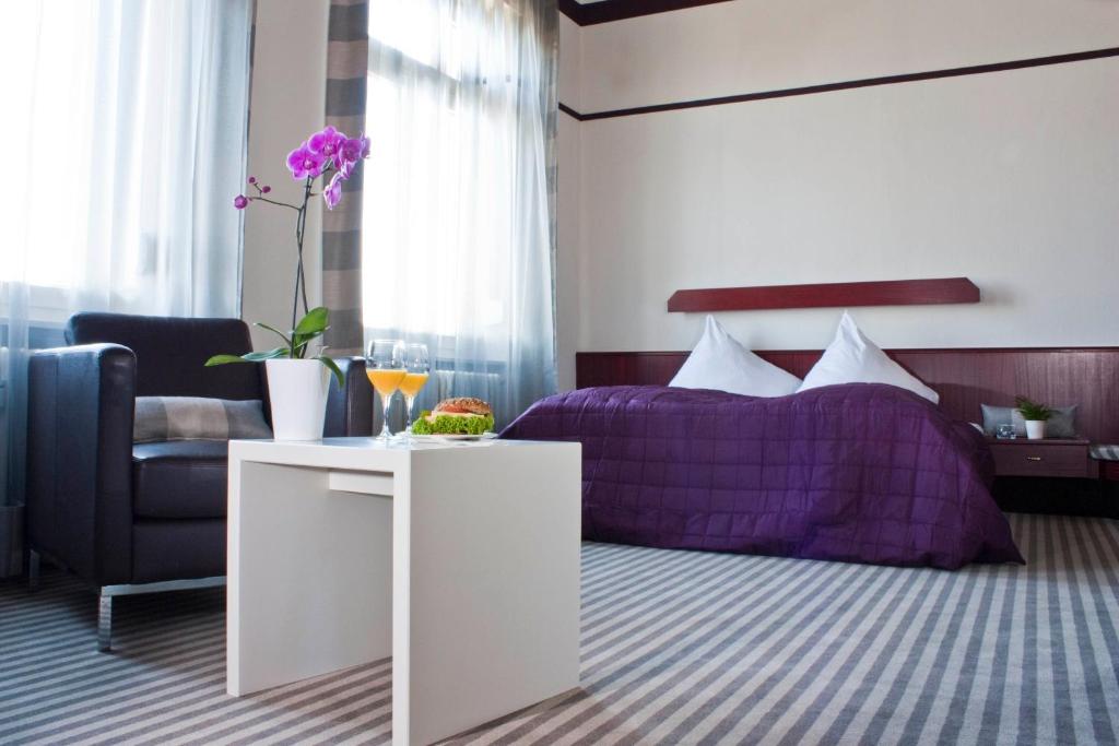 巴登-巴登新卡尔赦弗酒店的一间卧室配有一张紫色的床和一把椅子