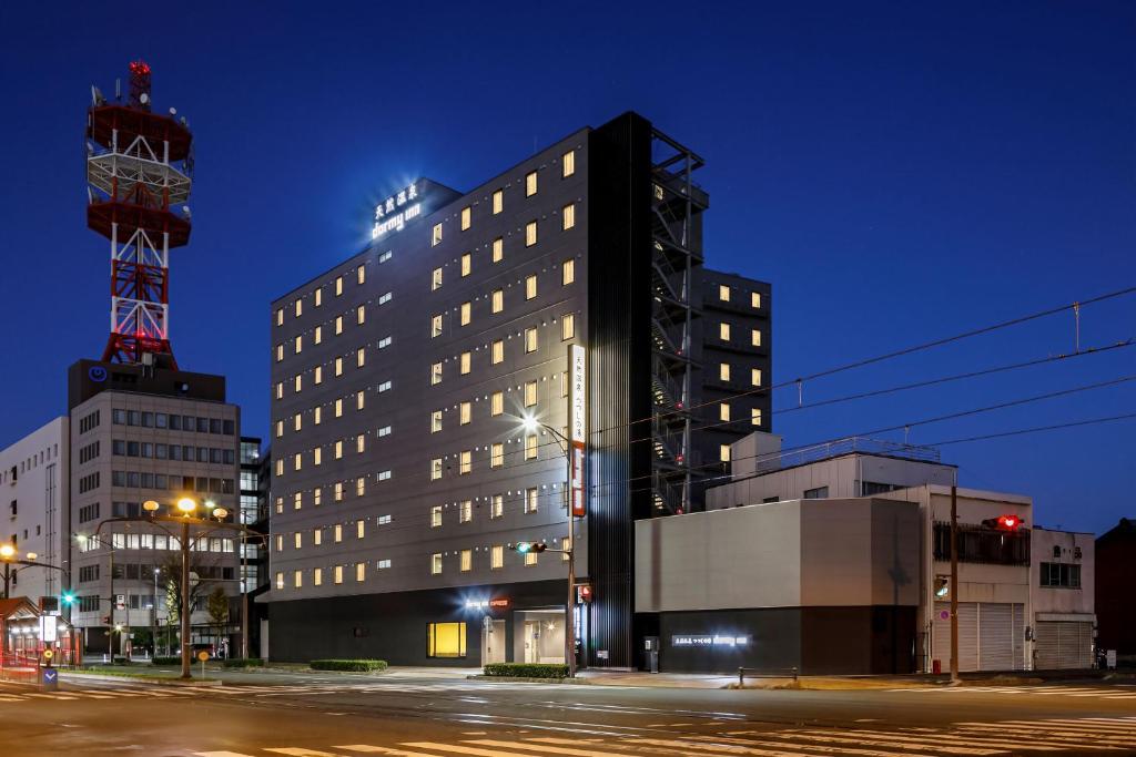 丰桥市Dormy Inn Express Toyohashi的夜幕降临的城市街道上一座高大的黑色建筑