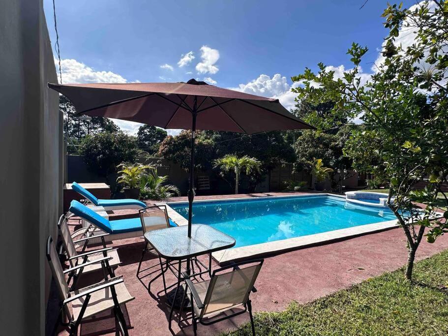 SiguatepequePayes Home的游泳池旁带遮阳伞的桌子