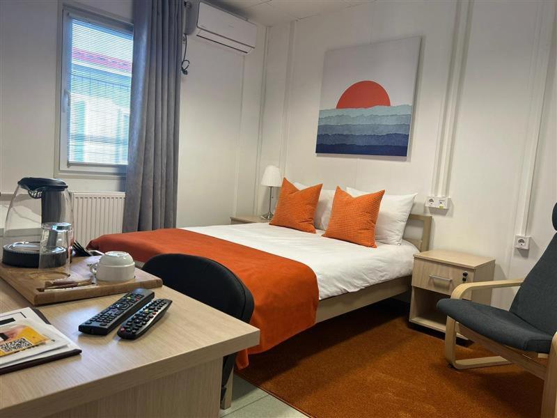 TengizBirlik的一间卧室配有一张带橙色枕头的床和一张书桌
