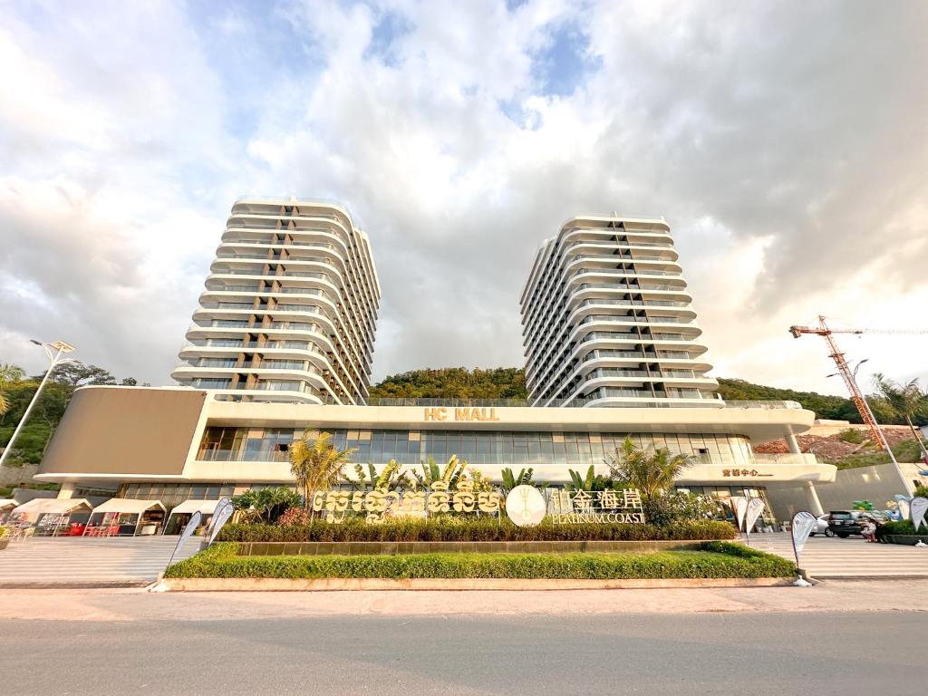 西哈努克Ark Seaview Holiday Inn的两座高大的白色建筑,前面有棕榈树