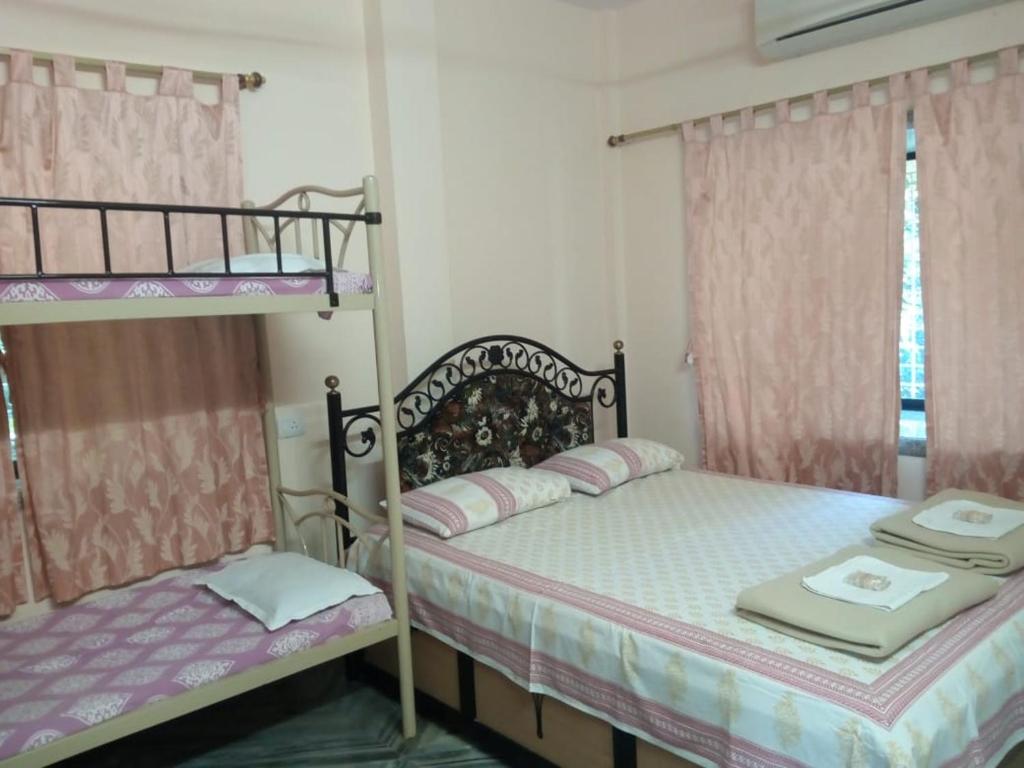 BhogweGovindaashram的卧室设有两张双层床,配有粉红色窗帘