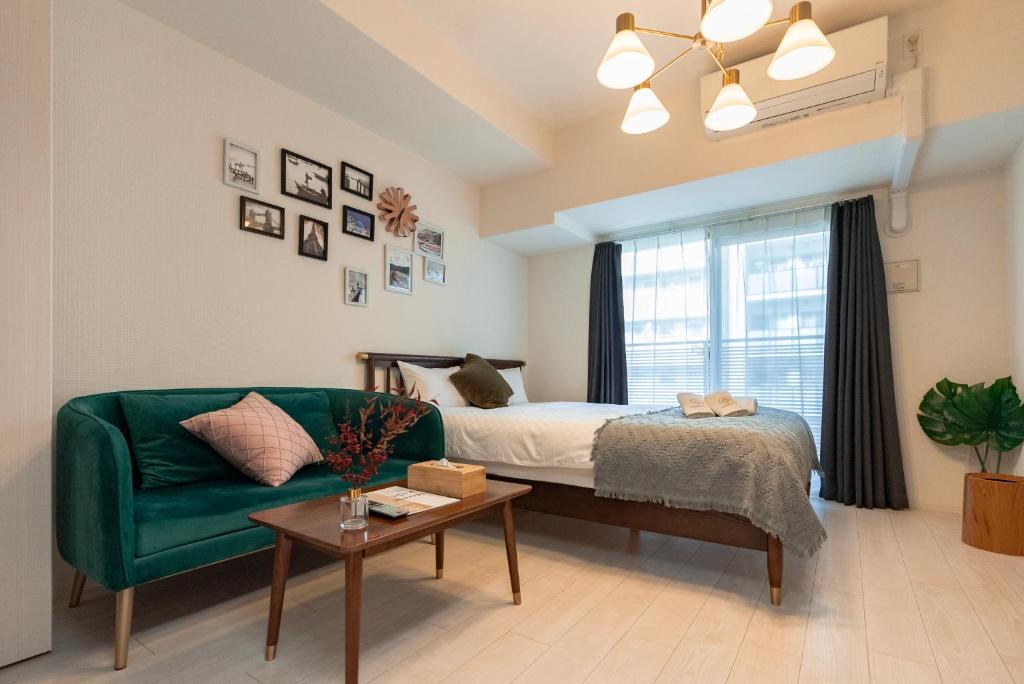 大阪谷町君ホテル　難波80的一间卧室设有绿色沙发、一张床和一个窗户。