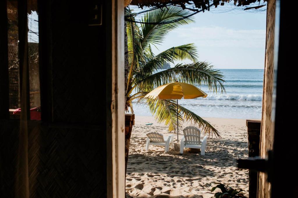 爱妮岛Bucana Beach Camp的享有海滩美景,配有两把椅子和一把遮阳伞