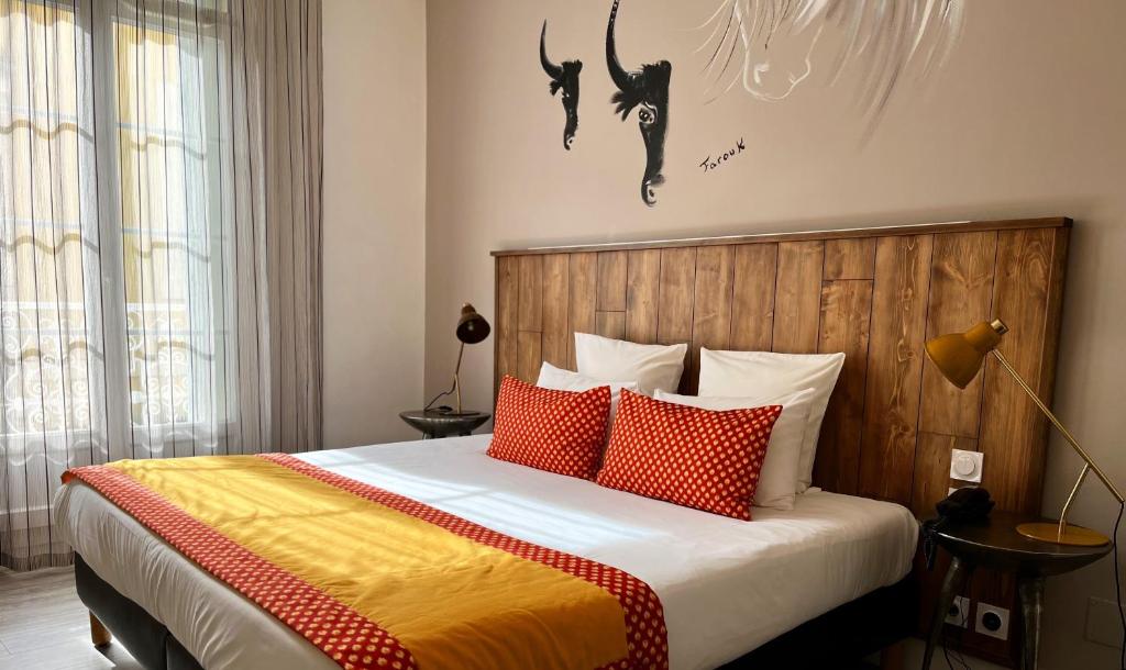 艾格-莫尔特圣路易斯酒店的一间卧室配有红色和橙色枕头的床