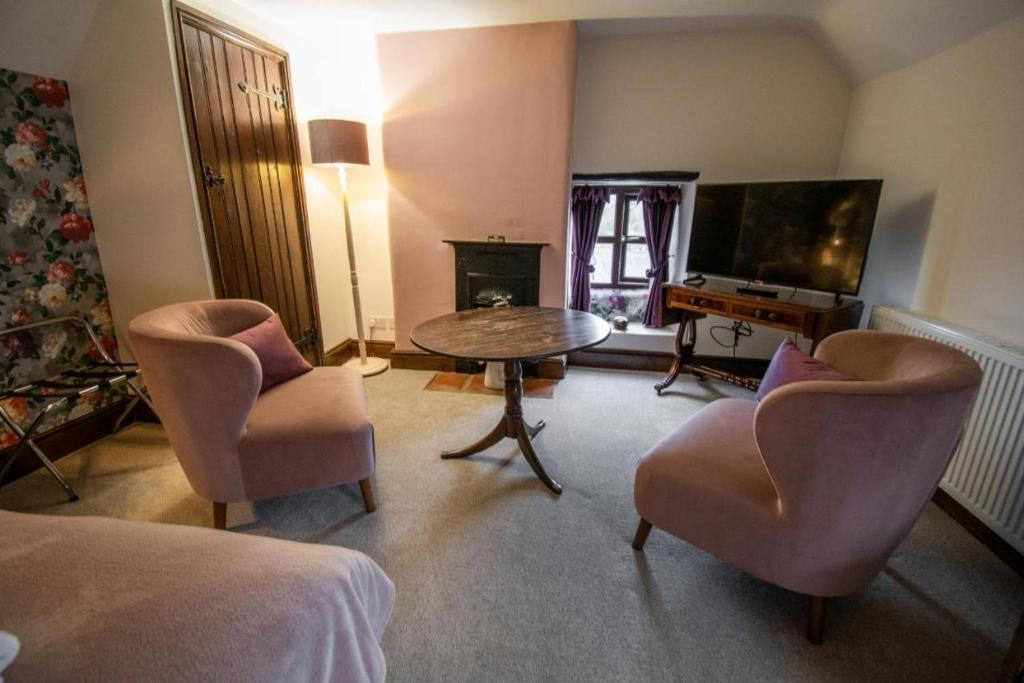 CottinghamThe Royal George的客厅配有桌椅和电视。