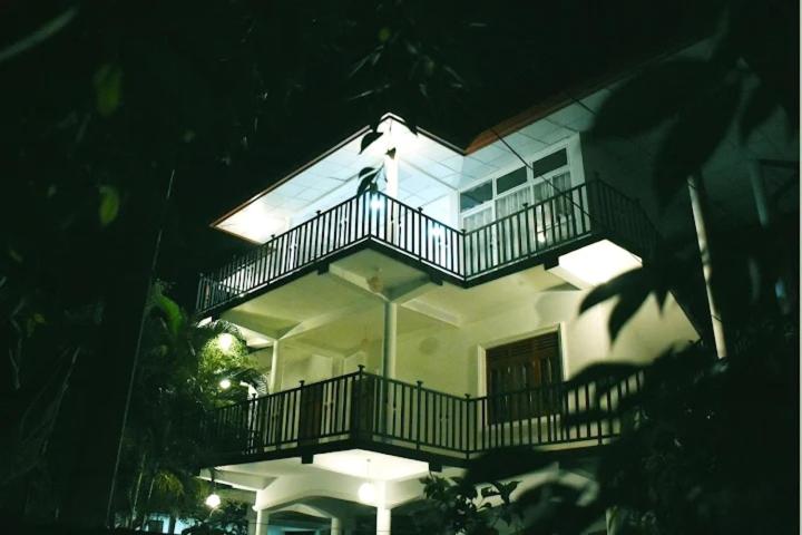 达瓦拉维Royal Inside Hotel的大型白色房屋 - 带灯阳台