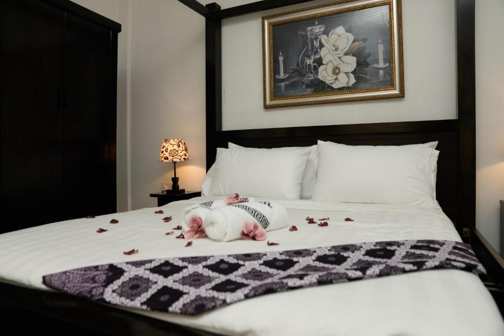 马六甲Putera Island Resort的一只狗躺在床上,床上有花瓣