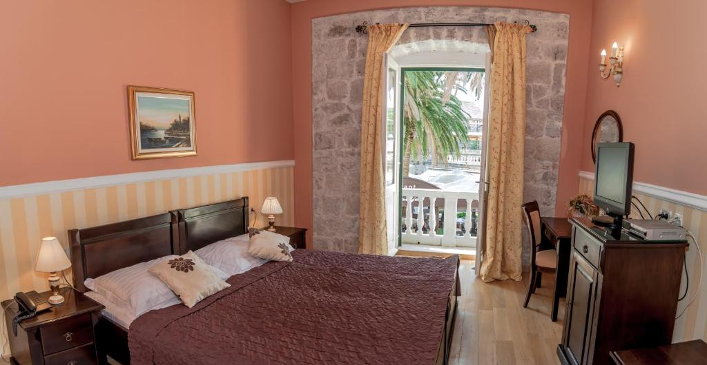 察夫塔特Boutique Hotel Villa Pattiera的一间卧室配有一张床、一台电视和一个窗口