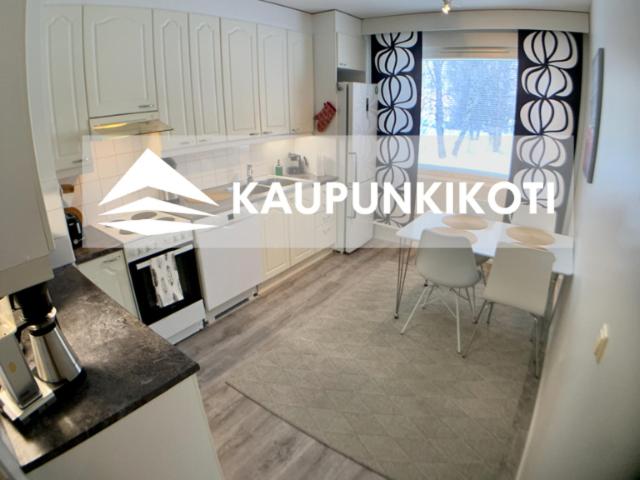 凯米Kaupunkikoti的厨房配有白色橱柜和桌椅