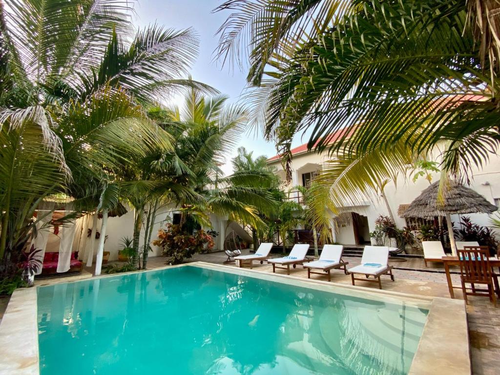 帕杰CeZeRe THE PALM HOTEL的一个带椅子的游泳池,棕榈树