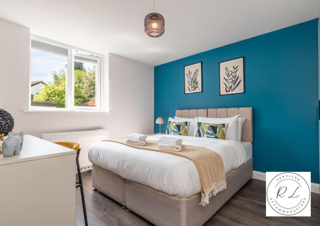 GlenfieldComfy Modern 2 Bed near Glenfield Hospital, sleeps up to 6的一间卧室设有一张蓝色墙壁的大床