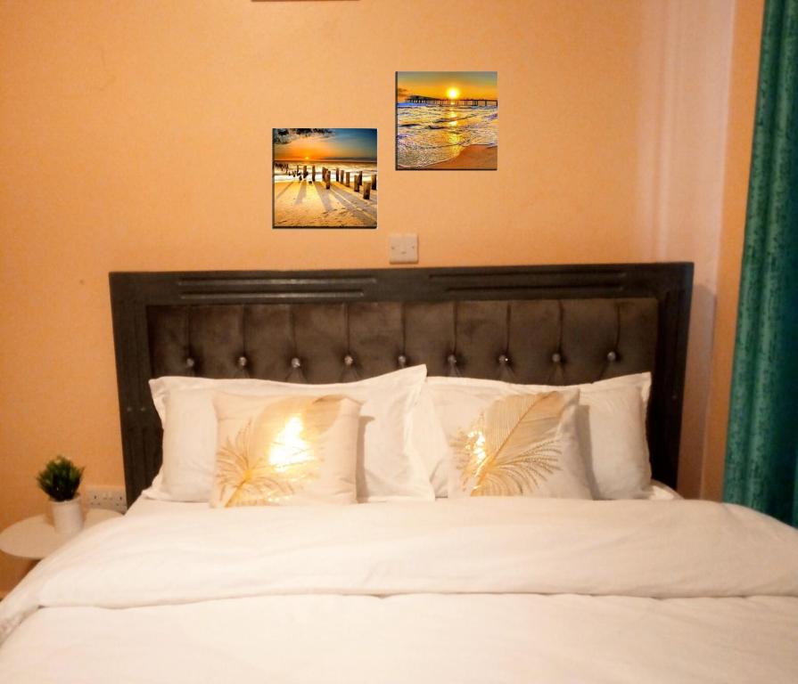 EmbuT Tree Paradise Apartments Embu的卧室配有一张白色床,墙上挂有两张照片