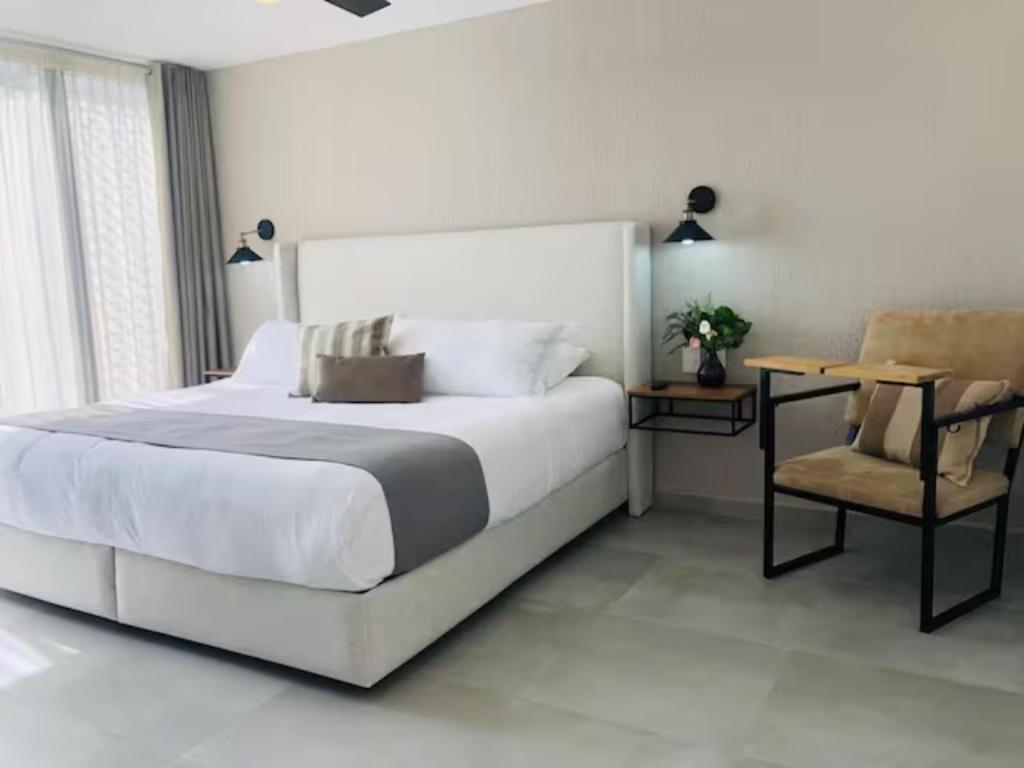 瓜达拉哈拉Urban Chapalita的白色卧室配有一张大床和椅子