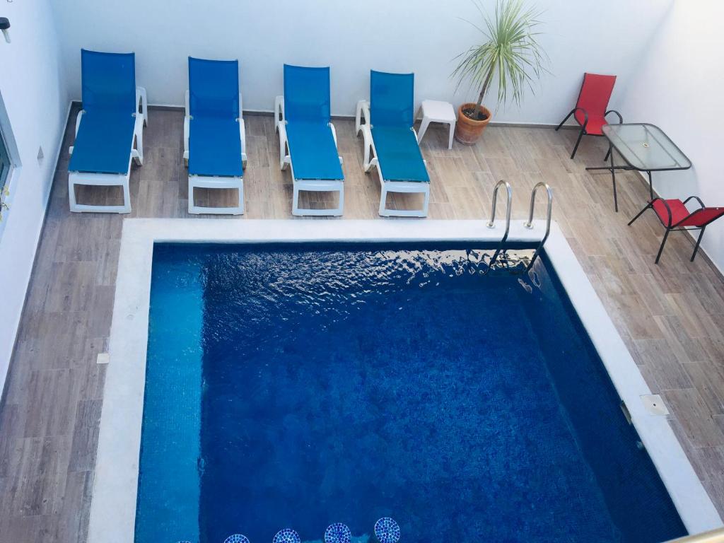 普拉亚卡门Casa Ohana By Utopia的游泳池旁设有蓝色和红色椅子