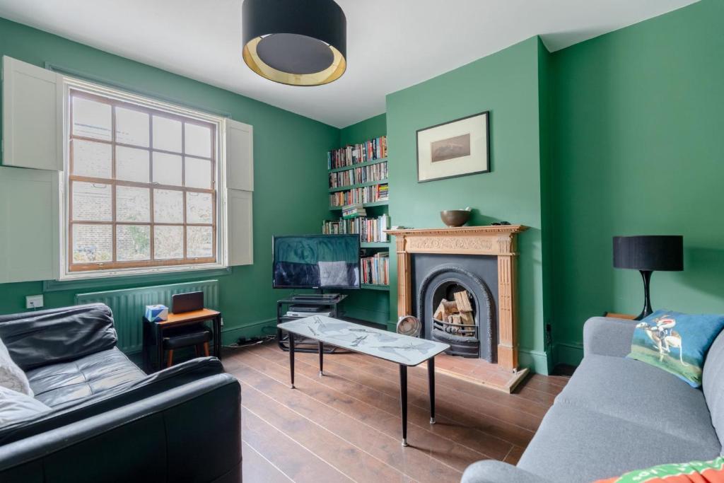 伦敦Trendy 2BD House 5 Mins from Willesden Junction!的客厅设有绿色的墙壁和壁炉