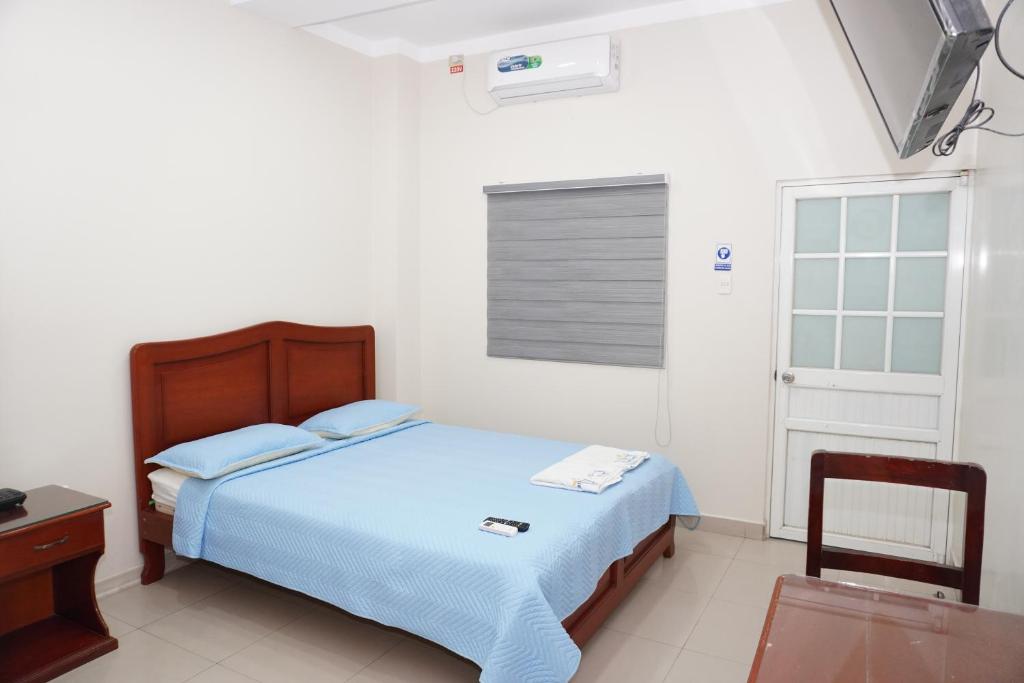 HuaquillasHotel SMIR的一间卧室配有一张床、一张桌子和一个窗户。