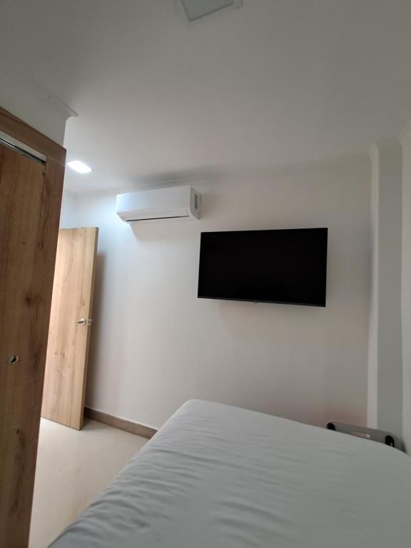 瓜亚基尔Ultra mini suite privada con baño的卧室配有一张床,墙上配有电视
