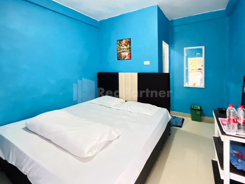 不拉士打宜Penginapan Gindo Sidebuk Debuk Berastagi RedPartner的卧室拥有蓝色的墙壁和白色的床。