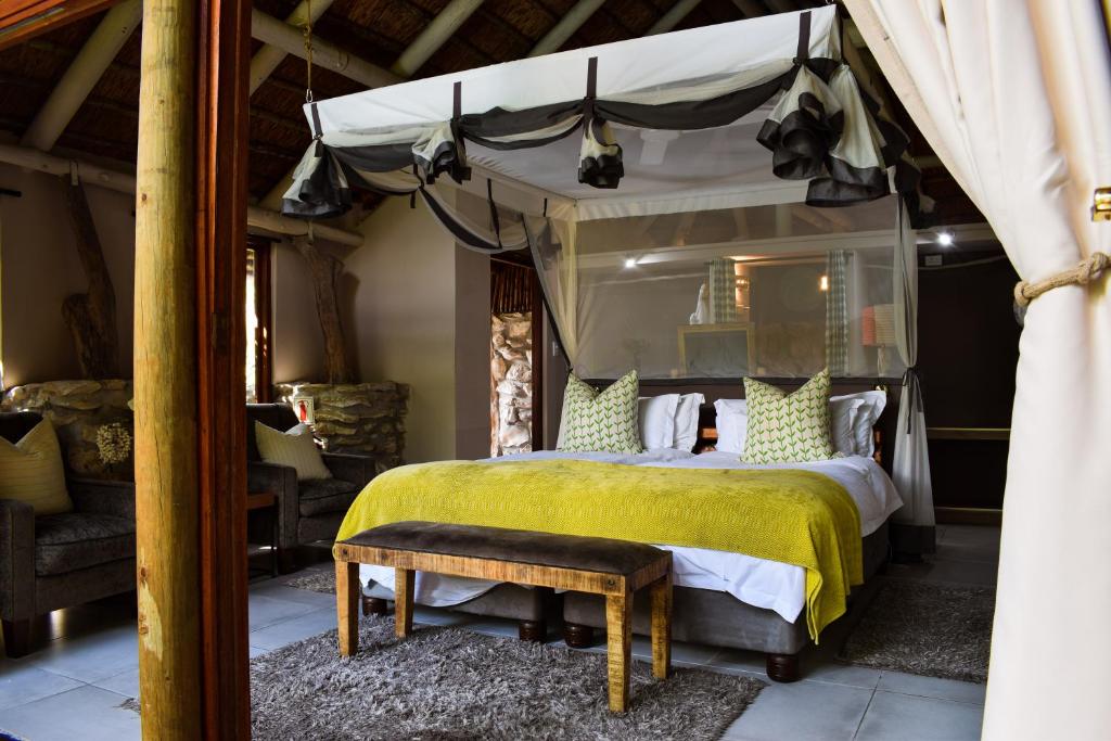 斯坦福Mosaic Lagoon Lodge的一间卧室配有一张带黄床罩的天蓬床