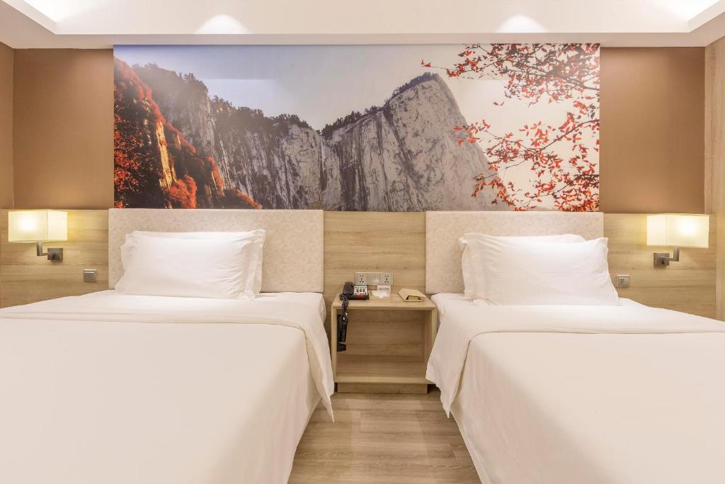 西安西安小寨石油大学亚朵酒店的墙上画画的房间里设有两张床