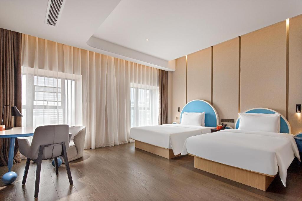 广州广州高铁南站亚朵酒店的酒店客房配有两张床和一张书桌