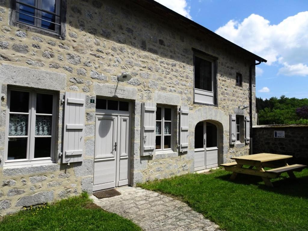 Saint-AngelGîte de France Maison raymond épis - Gîte de France 804的石制建筑,设有白色门和野餐桌