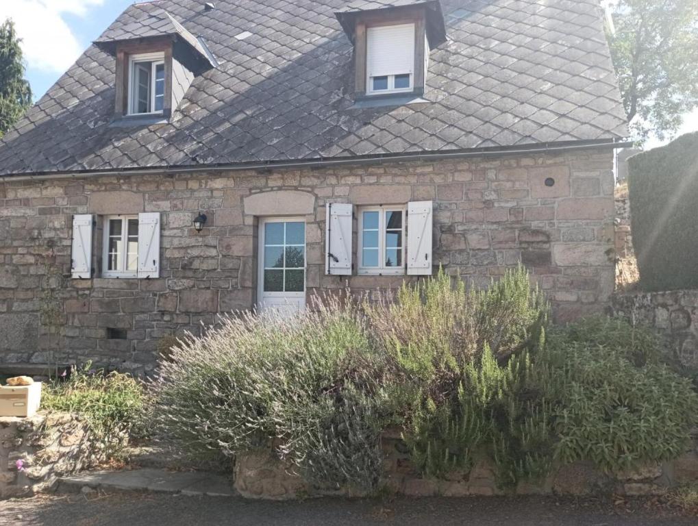 Gîte de France Gîte des veyssières 3 épis - Gîte de France 4 personnes 654的一座带白色窗户和灌木的古老石头房子