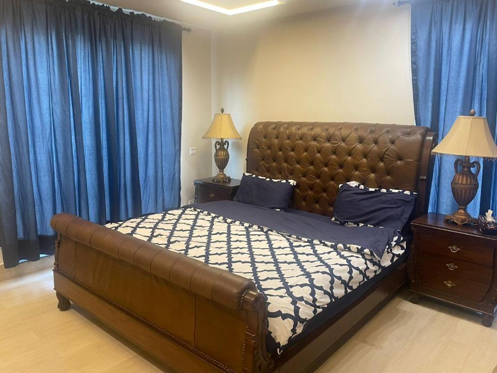 拉合尔Grey Orchard Homestay - A Family Place的一间卧室配有一张带蓝色窗帘的大床