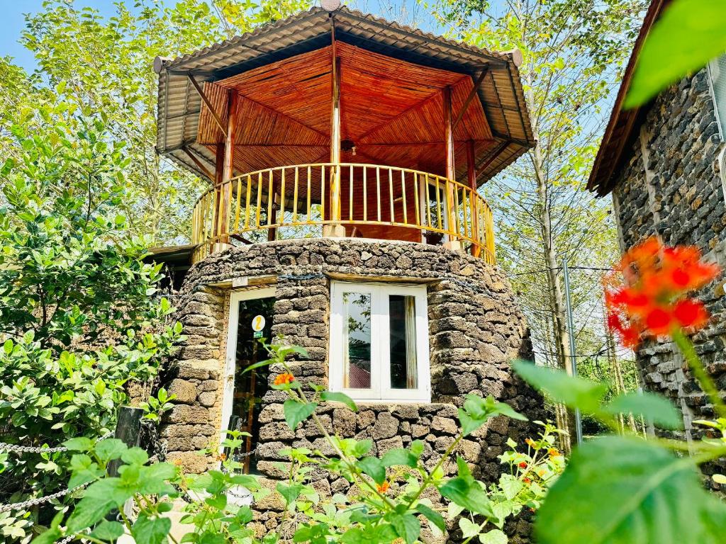 吉仙Lava Rock Viet Nam Lodge Anhfly Resort Nam Cát Tiên的一座小石头建筑,上面设有一个阳台