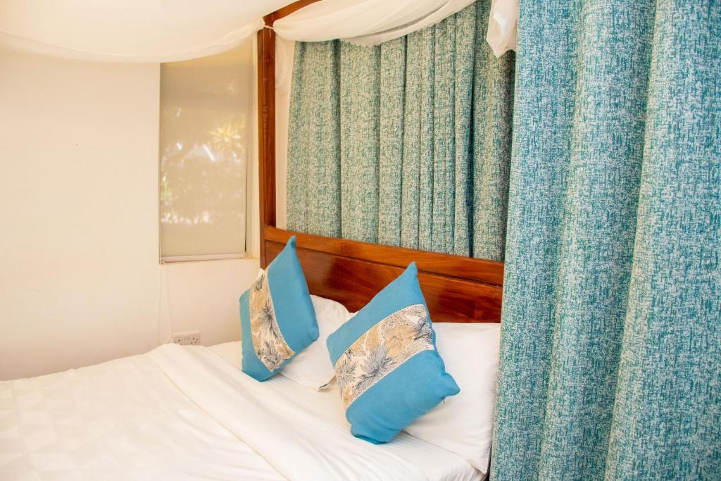 基苏木Harry's Kisumu Oasis的一间卧室配有一张带蓝色和白色枕头的床