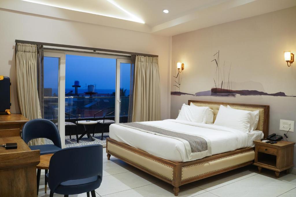 莫尔吉姆Ariena by Spree Hotels Goa的一间带一张床和一张书桌的卧室以及一个阳台