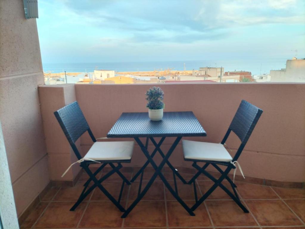 加鲁查El Mirador de Garrucha的阳台上的桌子、两把椅子和盆栽植物