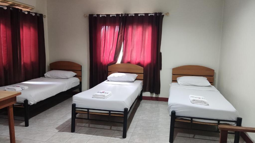 素可泰Toon guesthouse的配有红色窗帘的客房内的两张床