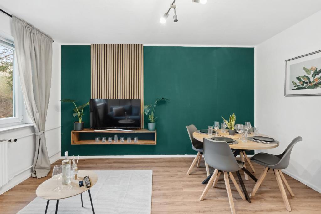 汉诺威Stadt-Apartment 3 Zimmer mit Terasse的一间拥有绿色墙壁和桌子的用餐室以及一台电视
