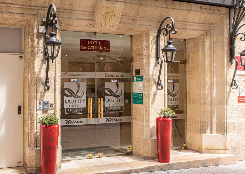 波尔多波尔多中心品质酒店的商店前有两只红色花瓶的建筑