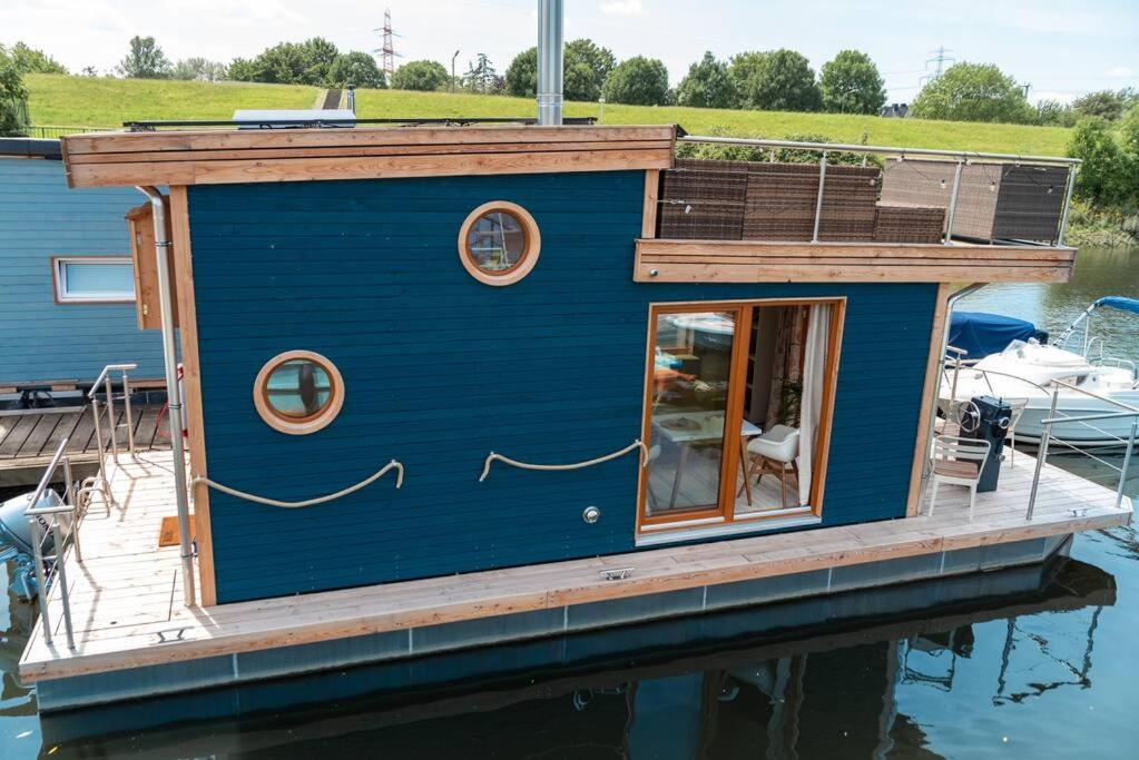 汉堡Tiny-Hausboot mit Kamin und Dachterrassenlounge的水面上码头上的一个小房子