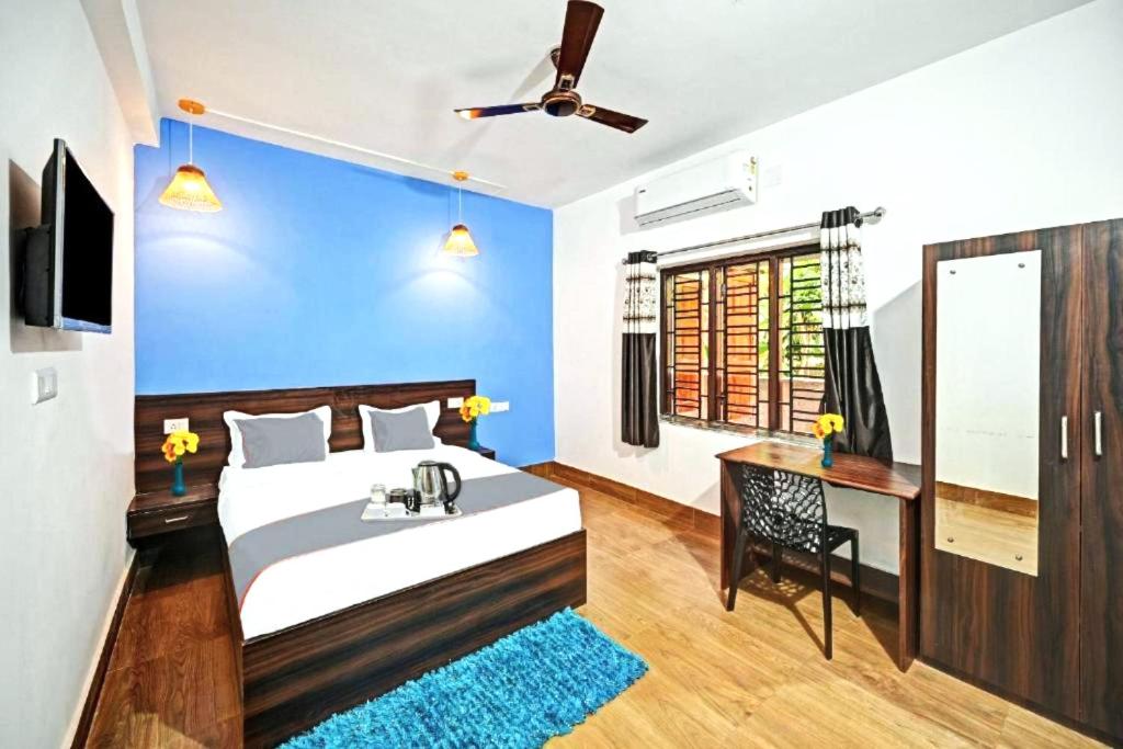 布巴内什瓦尔Goroomgo Madison Blue Bhubaneswar的一间卧室配有一张床、一张书桌和一个窗户。