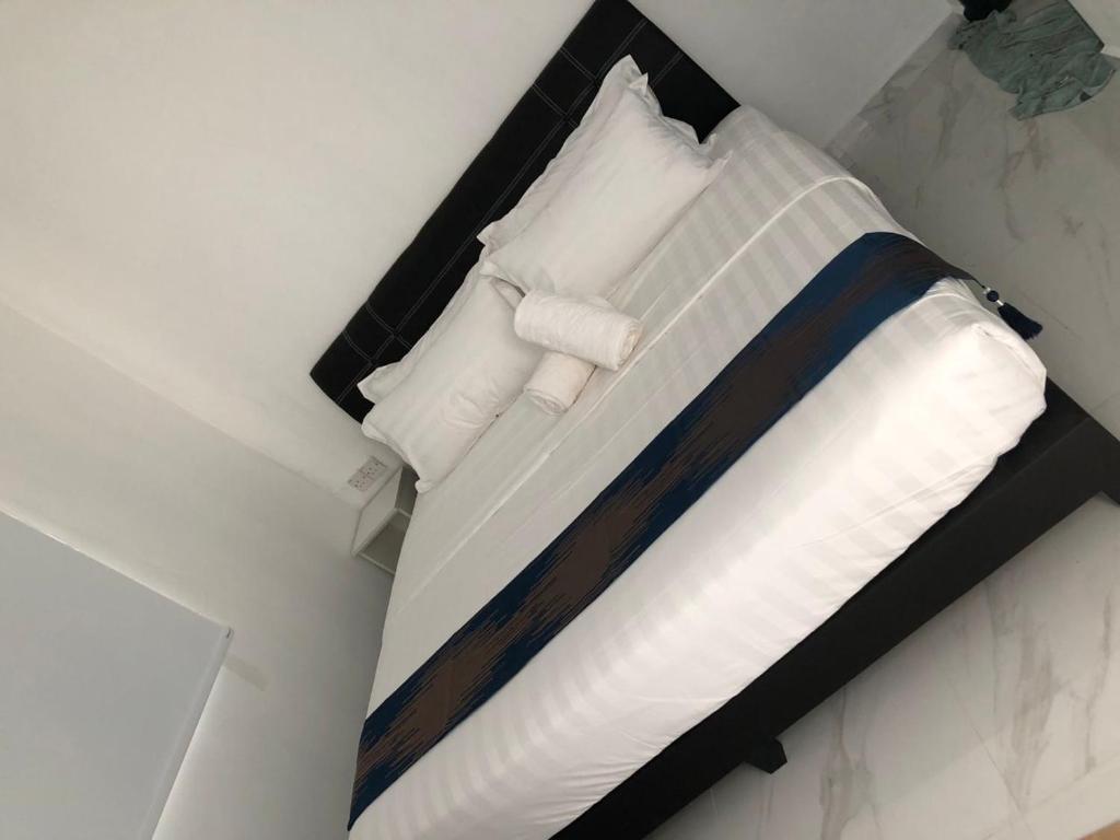 怡保SAMMY HOOMESTAY的一张带白色床单和枕头的床