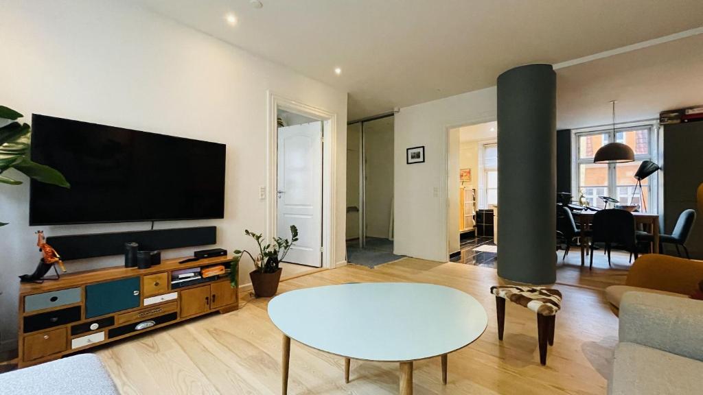 哥本哈根ApartmentInCopenhagen Apartment 1580的客厅配有平面电视和桌子。